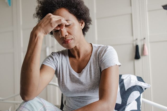 older Black woman with eyes closed and fingers over her eyes, seemingly looking cynical or pessimistic