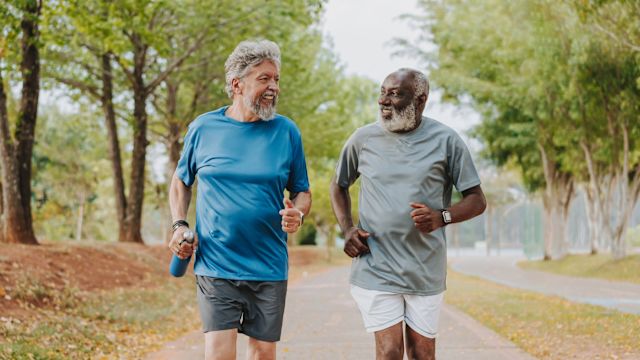 Two older men go for a jog in a park together. Social support can make an important difference when working toward health and fitness goals.