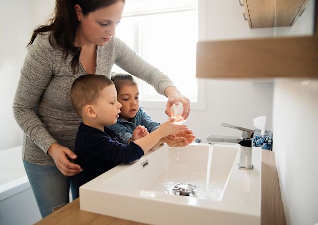 mother showing two kids how to wash hands properly