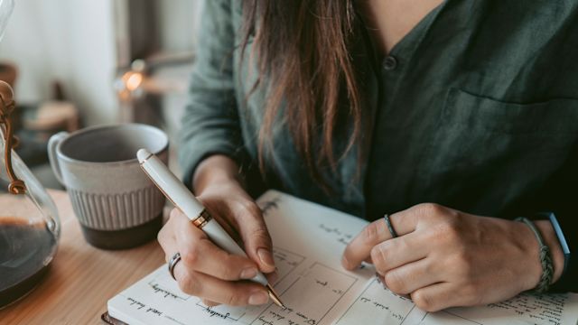A woman writes down the details of a recent hot flash in a vasomotor symptoms (VMS) journal.