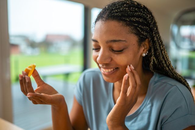 young black woman happily eating an orange