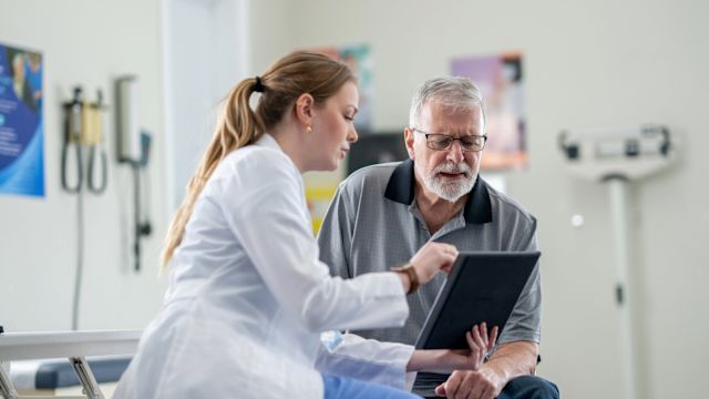 An oncologist uses a tablet to explain test results to a senior male patient who has been diagnosed with MDS.