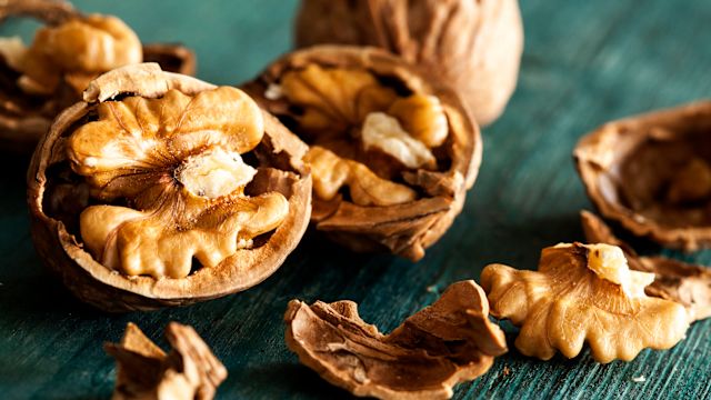 Cracked walnuts and shells on a green table.