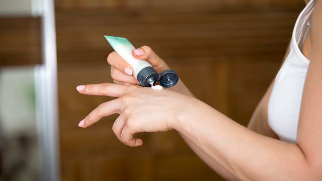 A woman applies an antihistamine lotion to help ease itching caused by chronic hives.