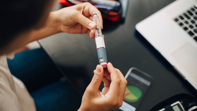 A woman reads the instruction label for an injectable biologic medication. The therapies a person uses to treat atopic dermatitis can change over time.