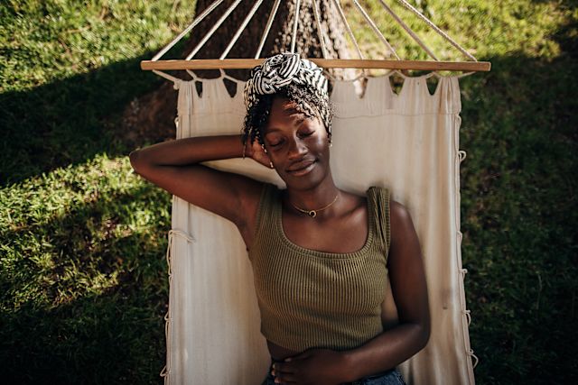 A smiling woman with psoriasis lying back on a hammock to relieve stress