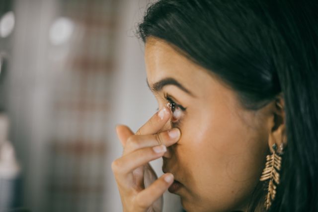 woman placing contact lens in eye