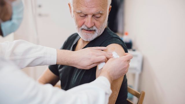 A senior man receives an updated COVID vaccine at his healthcare provider's office.
