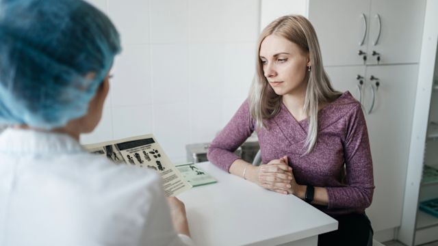 A young woman and her oncologist review patient education materials at an appointment to discuss treatment for a rare type of ovarian cancer.