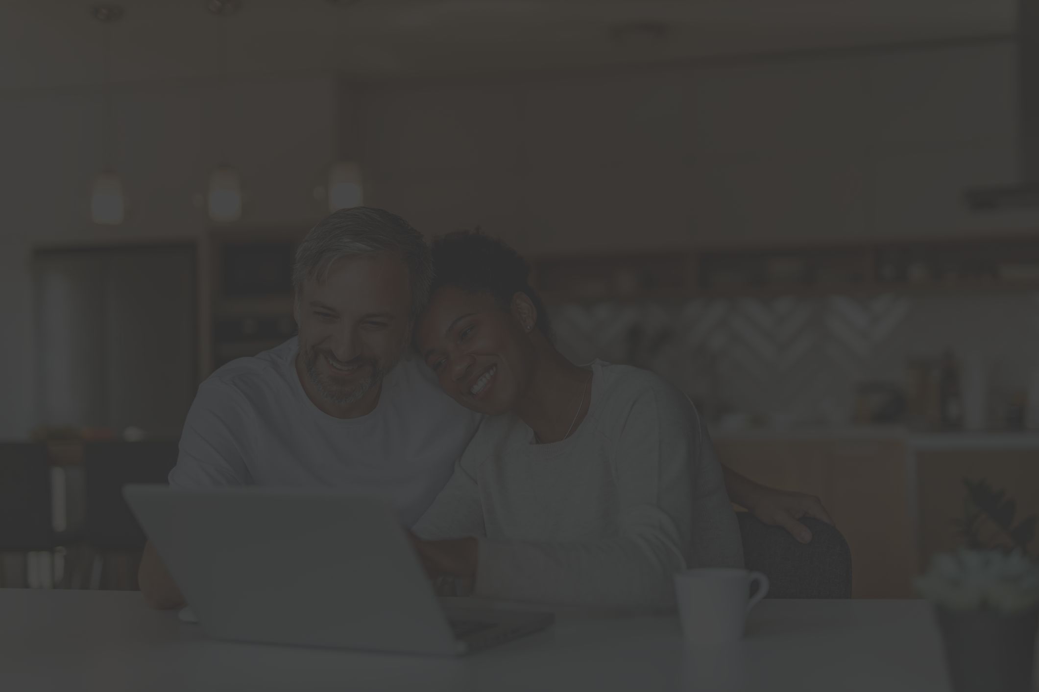 mixed-race middle aged couple sit happily at computer