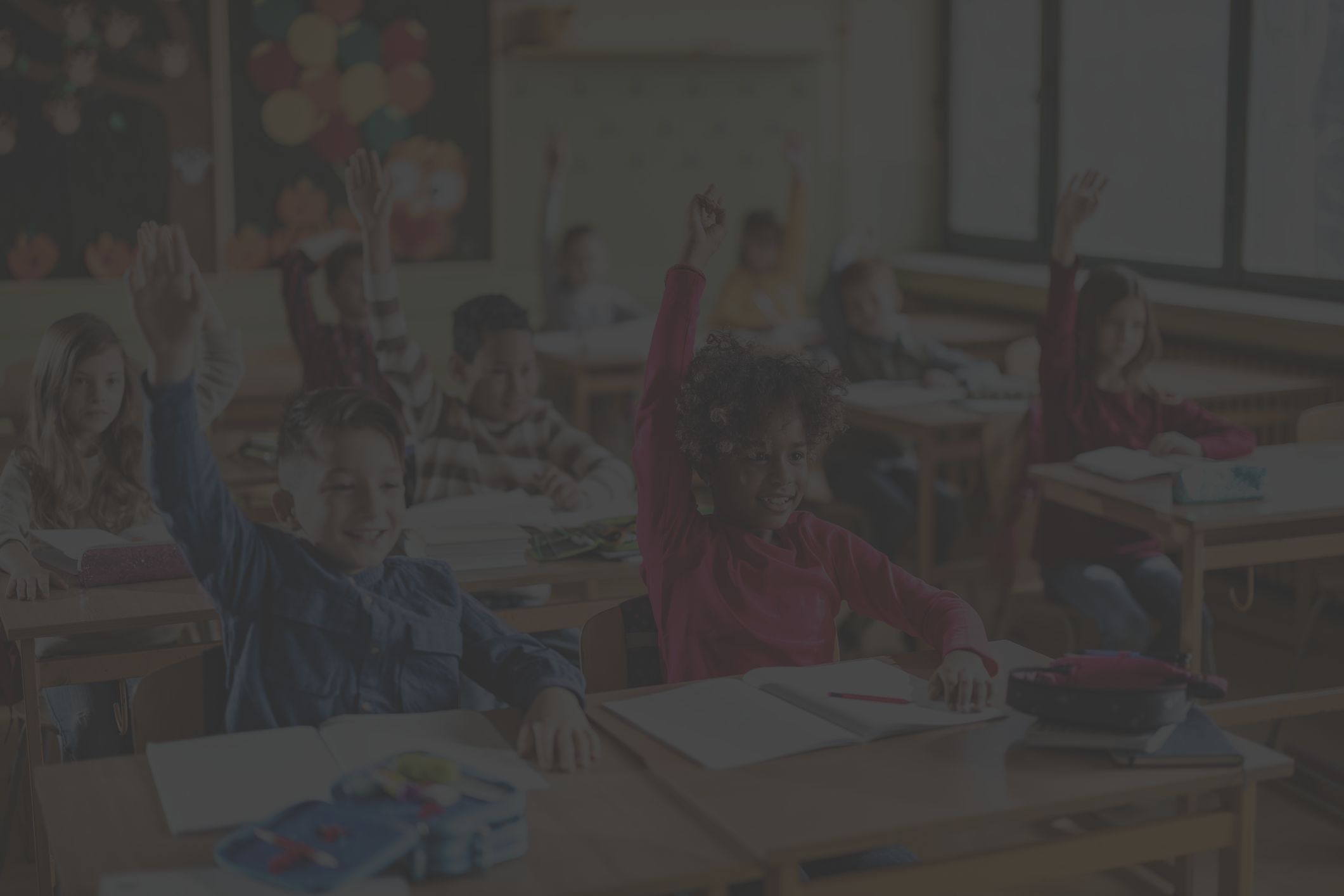 children raising hands in classroom