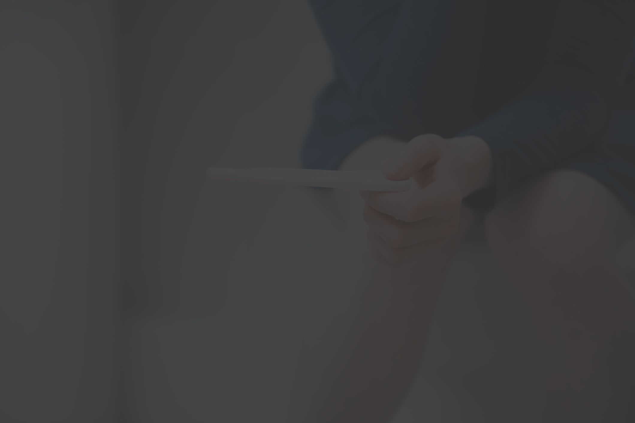 Lower legs of someone sitting on a toilet and holding a home pregnancy test