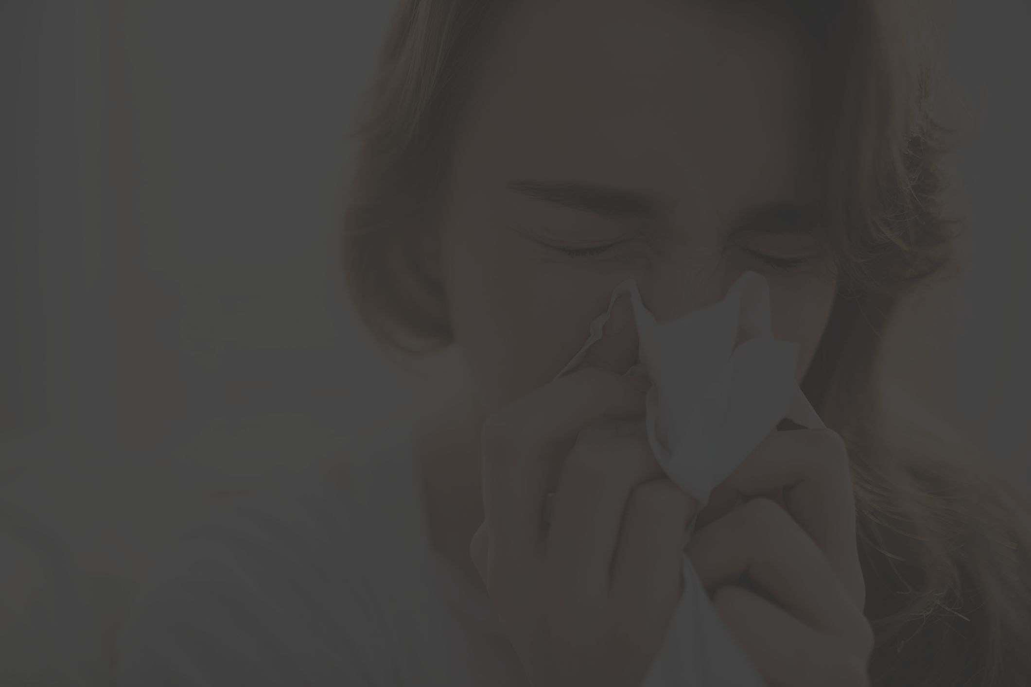 young woman blowing nose sneezing indoors