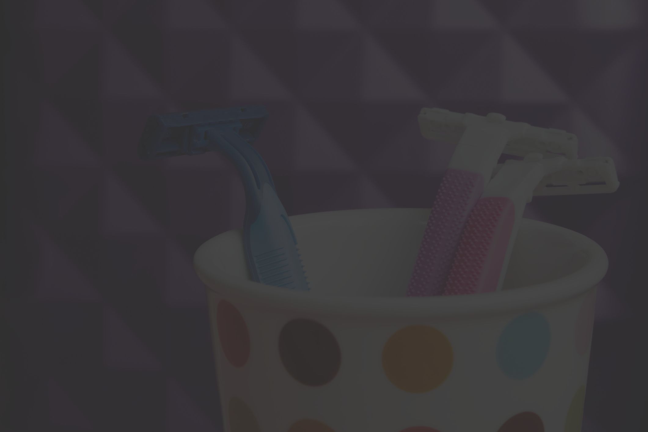 brightly colored razors in polka-dot cup