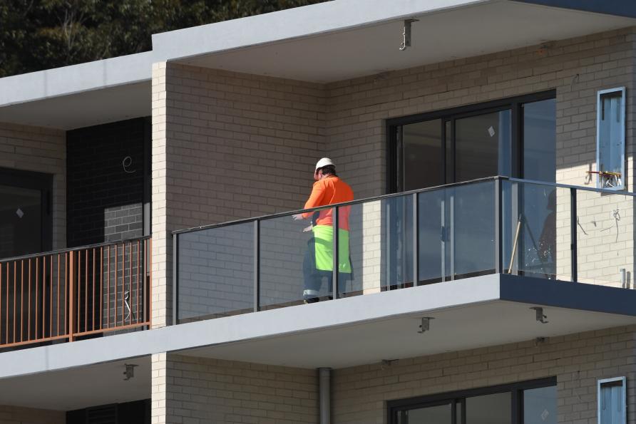 Person in hardhat and high-vis jacket standing on a balcony under construction