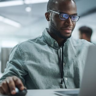 Square image of IT man working at laptop in an office